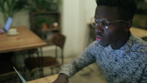 Ernsthafter-Afroamerikanischer-Mann,-Der-Im-Café-Einen-Laptop-Benutzt